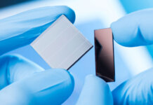 Australia’s next-gen solar PV centre scores $95.4M funding Gloved hands hold tiny solar cells (inhdo-pacific)