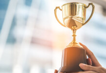 ElectraNet recognised as global ESG leader for third year Hand holding trophy with buildings in background (quinbrook)