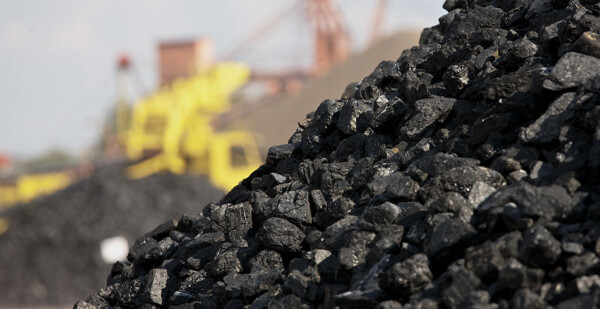 Close up of coal mound with industrial machinery in background (coal super fund)