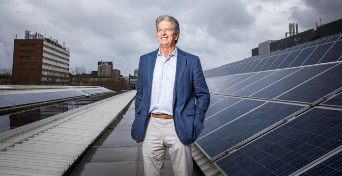 Scientia Professor Martin Green stands next to rooftop solar panels with buildings in the background (solar pioneer)