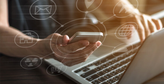 Woman holds smartphone while working on laptop with consumer data right concept icons set over the top of the image (AGL Biza.io)