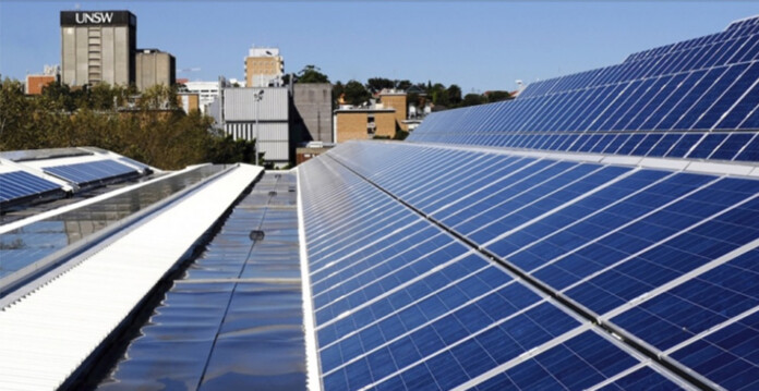 Solar panels on a rooftop with a UNSW building in the background (ultra low cost solar)