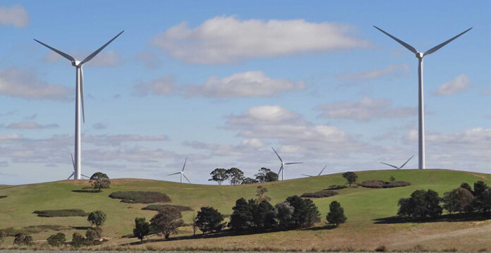 Wind turbines with rolling green hills against blue sky (harmonic compliance)