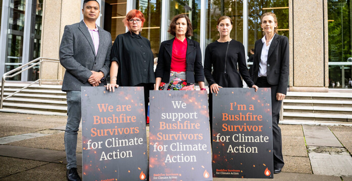 Bushfire survivors holding placards standing outside court