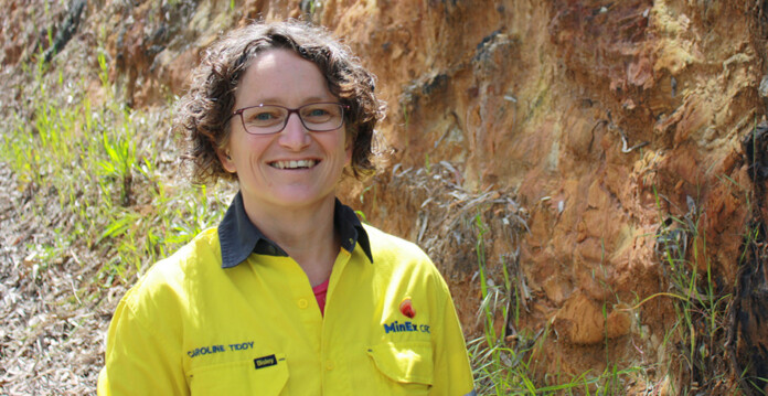 Geoscientist Caroline Tiddy in front of rock formation wearing high-visibility workwear