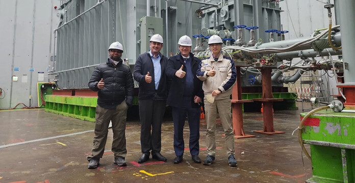 Engineers in hard hats standing in front of transformer (EnergyConnect)
