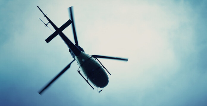 Helicopter flying across hazy blue sky (essential energy aviation)