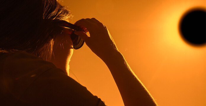 solar-eclipse Woman looks through dark sunglasses to view solar eclipse