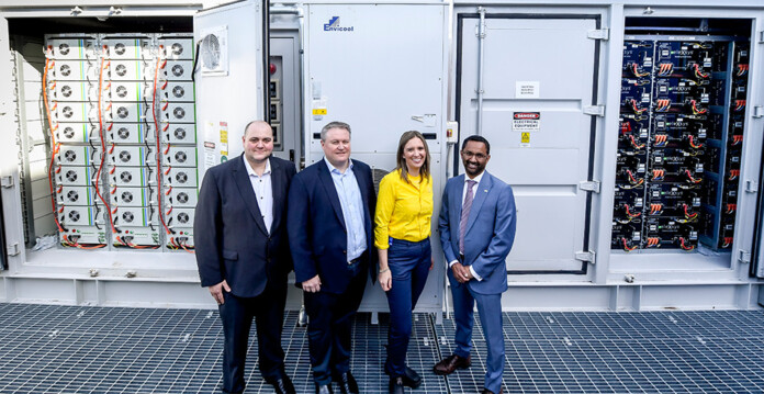 Executives standing smiling in front of large microgrid battery system at IKEA Adelaide
