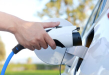 Australia’s energy ‘prosumers’ are transforming the grid Person's hand plugging charger into electric vehicle (consumer energy)
