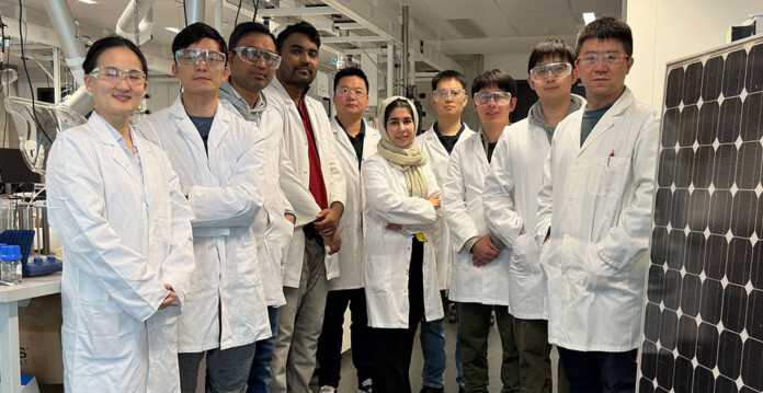 Researchers wearing lab coats standing in a group smiling (silver solar)