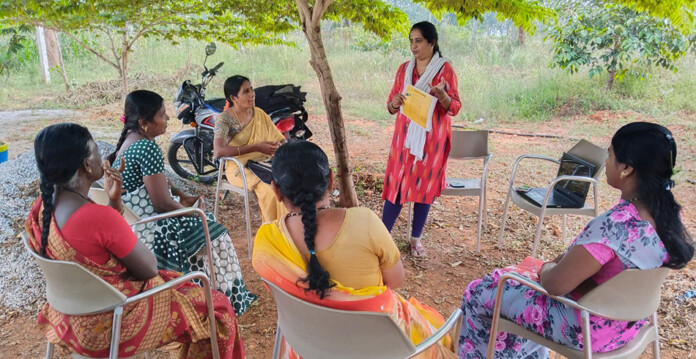 Pollinate-Group Group of "Suryamukhi", women aged 18-54 from various regions across India and Nepal, sit in circle listening to a female speaker (Flow Pollinate)