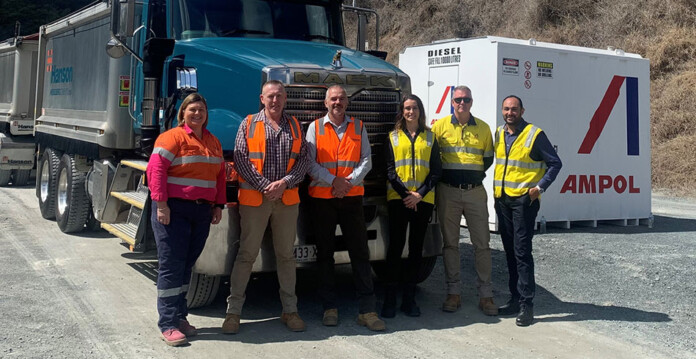 Ampol and Hanson executives in high-vis clothing standing in front of large truck and container with Ampol signage