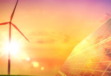 Energy affordability and net zero go together, report says Wind turbine with solar panels against beautiful sunny orange sky (renewables tender)