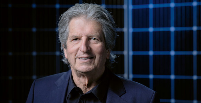 Professor-Martin-Green Distinguished looking man in suit smiles in front of solar panels