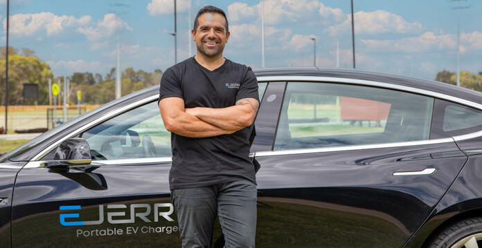 Ejerry Aussie electrician Joel Wille stands in front of electric vehicle (portable EV charger)