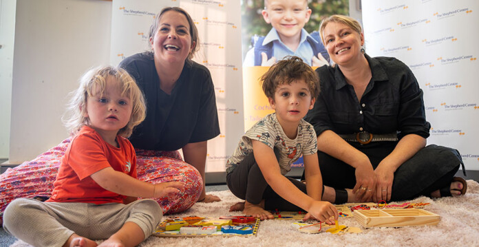 Two adult women smiling with young children at a community hearing centre (hydro grants)
