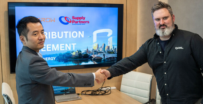 Two men shake hands in front of Sungrow and Supply Partners signage in boardroom