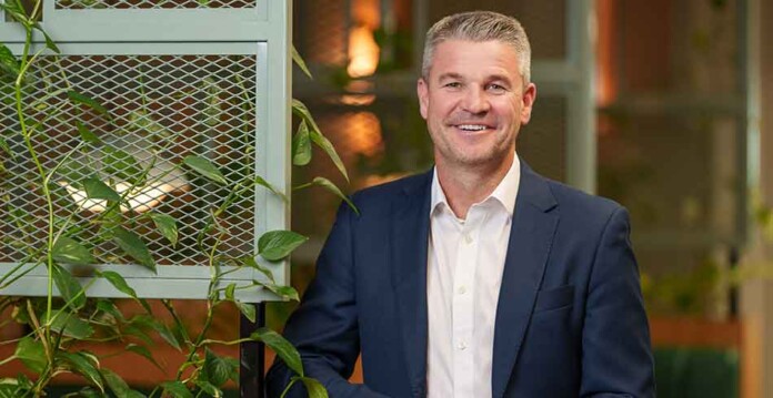 Smiling male executive wearing suit and posing for photo with foliage in the background