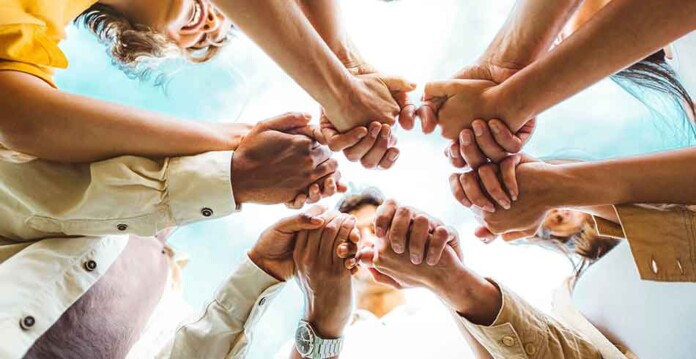 Community members join hands in the centre of a circle