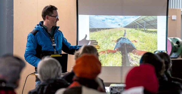 Man points to presentation slides while talking to group