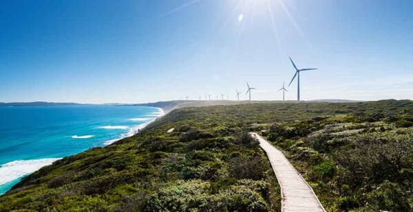 Wind turbines on coastline of beautiful beach in Australia with bright blue sky overhead