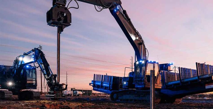 Two robotic construction machines install equipment at a solar farm site