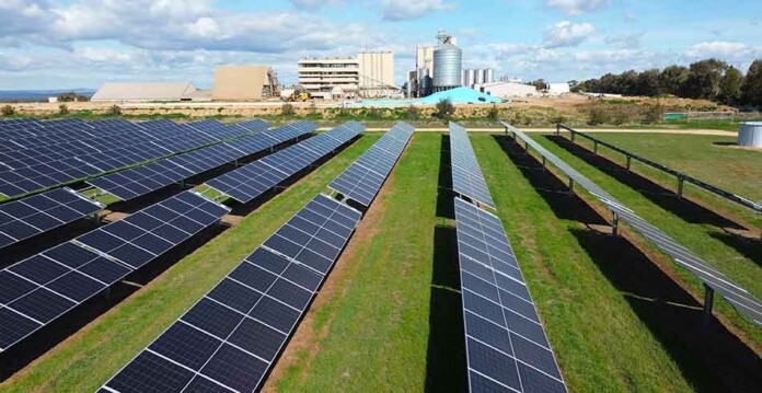 Close-up of solar PV arrays with oil processing plant in the background