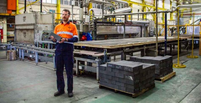 Man in high-vis safety wear stands in front of thermal energy storage bricks