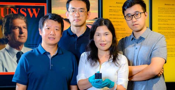 Researchers pose with kesterite solar cell in front of UNSW posters