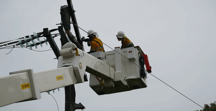 Ergon linesmen work in crane bucket to fix powerlines