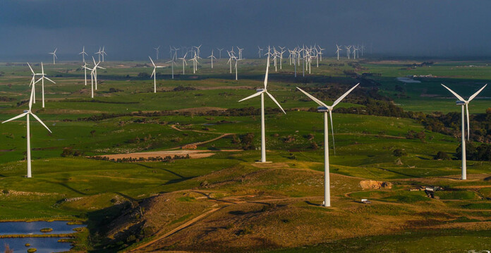 Wind turbines across grassy landscape with grey-blue sky overhead