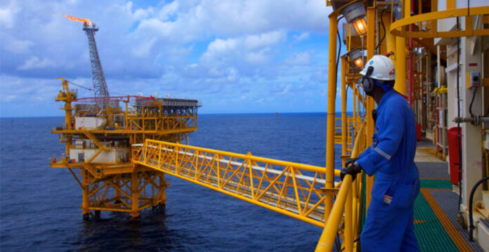 Offshore gas rig with worker in blue overalls and hard hat