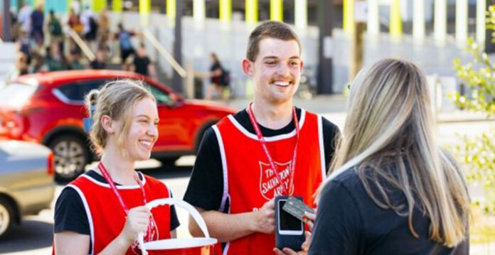 salvos Two The Salvation Army donation collectors smiling with blonde woman making a donation