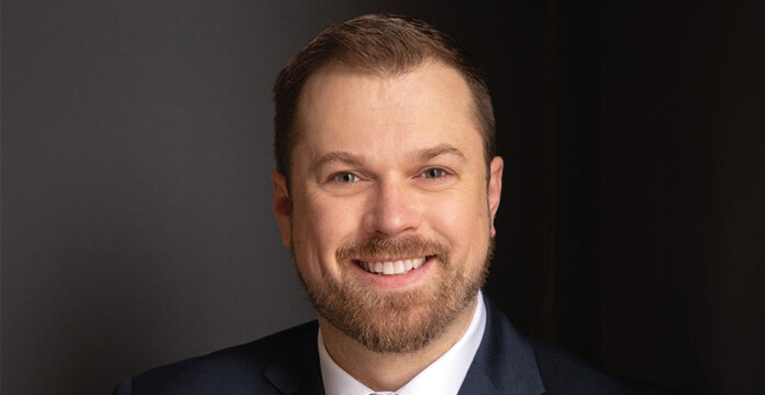 Head and shoulders shot of smiling male executive Shannon Hyde wearing white shirt and black suit