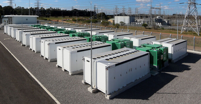 wallgrove-bess Battery units at a battery storage site with transmission towers in background