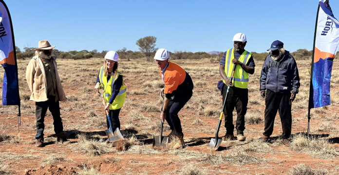 Officials and community members participate in a sod turning ceremony at grassy site with Horizon Power flags
