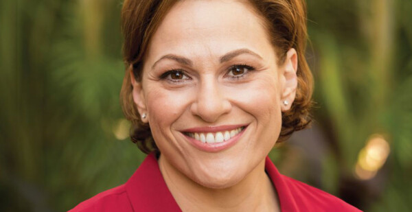 Head and shoulders shot of smiling woman with short brown hair wearing a red suit jacket