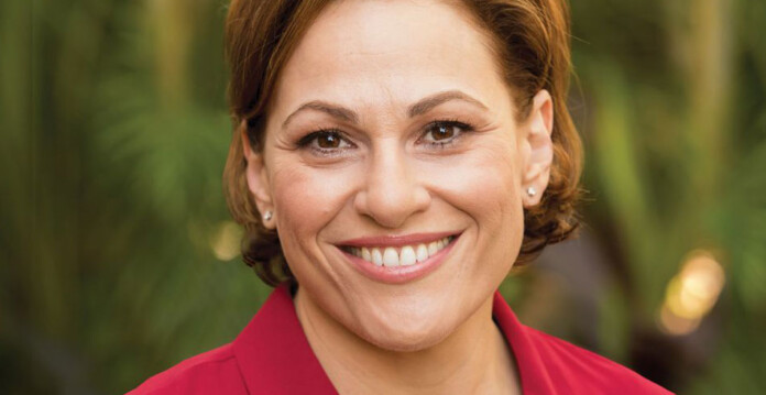 jackie-trad Head and shoulders shot of smiling woman with short brown hair wearing a red suit jacket