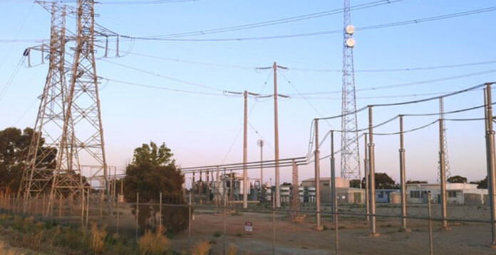 Transmission towers and associated infrastructure at site with blue sky overhead