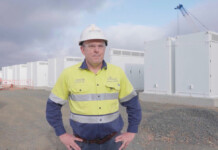Stanwell Board asks CEO to resign in “leadership transition” Executive in hard hat and safety workwear stands in front of Tesla Megapacks at battery storage project