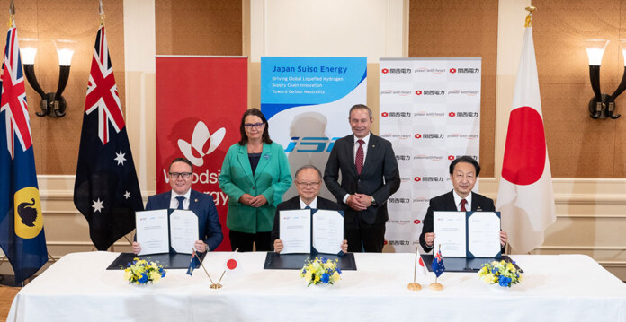 Japanese and Australian energy company officials at a desk for an agreement signing
