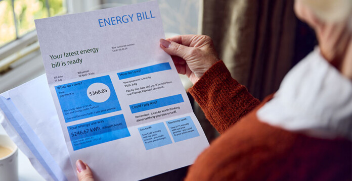 Senior woman holding electricity bill near window