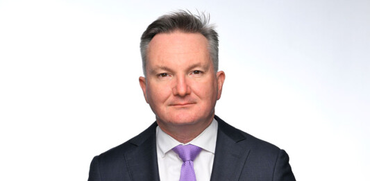 Headshot of male wearing dark suit and purple tie