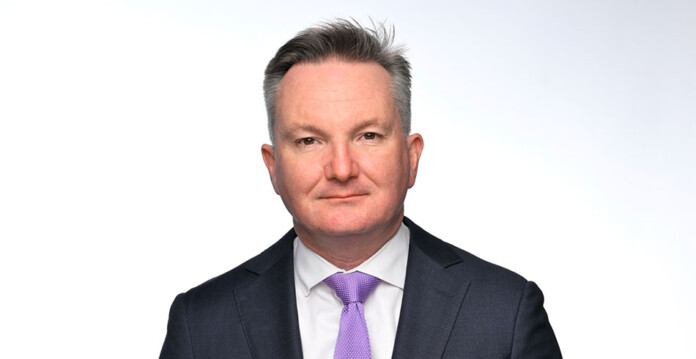 Headshot of male wearing dark suit and purple tie