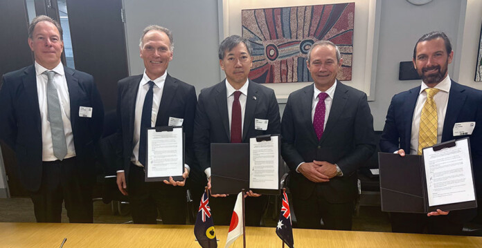 Officials in suits pose for photo with signed partnership agreement