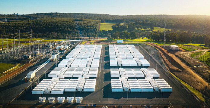 Aerial shot of white battery units at battery project with blue sky overhead
