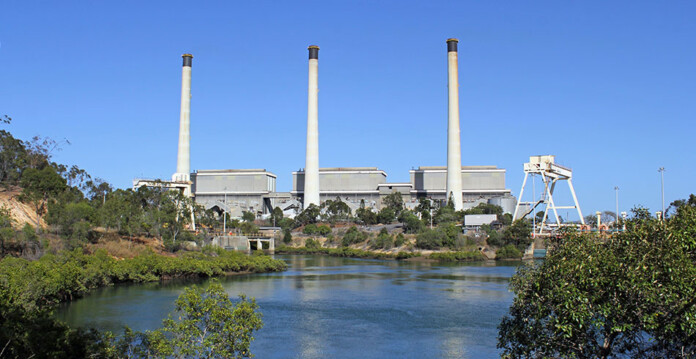 Coal-fired power station with three smoke stacks, and blue sky overhead