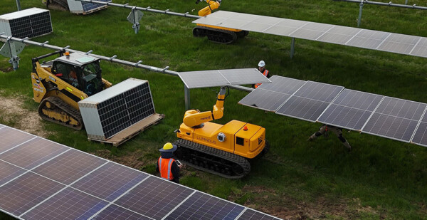 Yellow robots installing solar panels at solar farm site