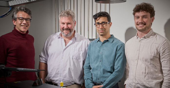 omega-silicon Four men standing side by side, smiling for photo